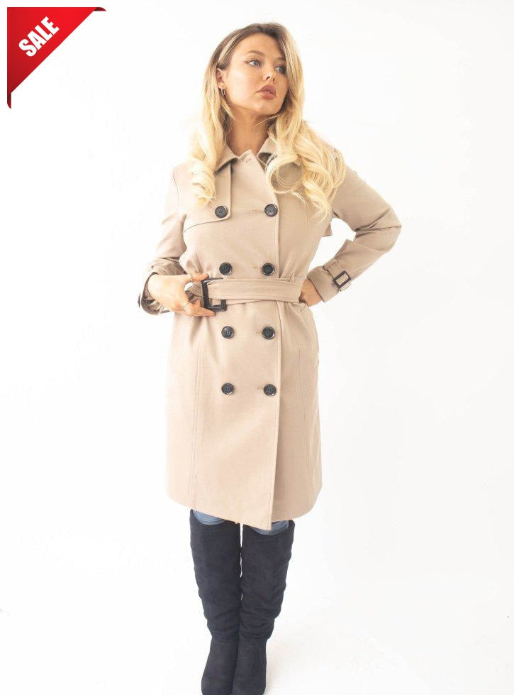 Woman wearing a beige trench coat with a sale tag on a white background