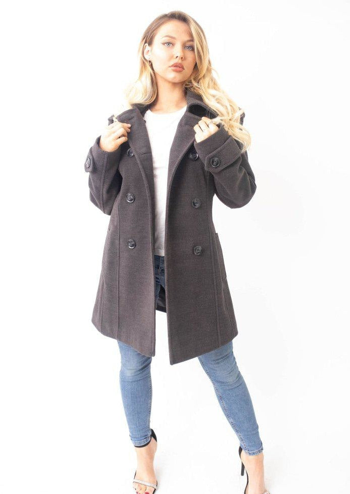 Woman wearing a gray coat and blue jeans on a white background