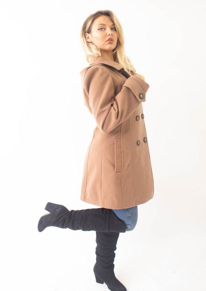 Woman wearing a beige coat and gray knee-high boots on a white background