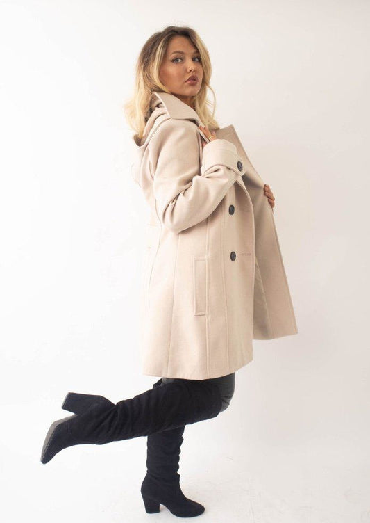 Woman wearing a beige coat and black boots on a white background