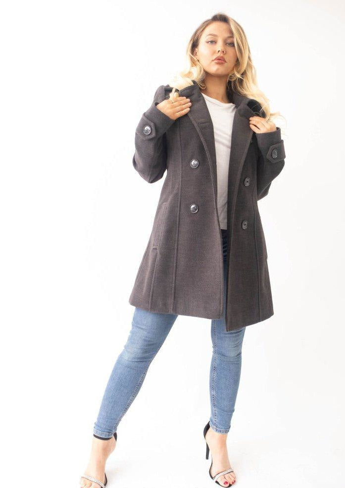 Woman wearing a gray coat and blue jeans on a white background