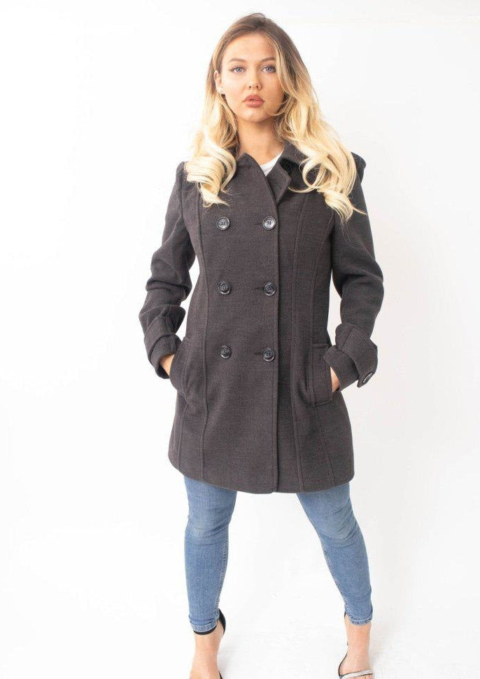 Woman wearing a dark gray coat and blue jeans on a white background