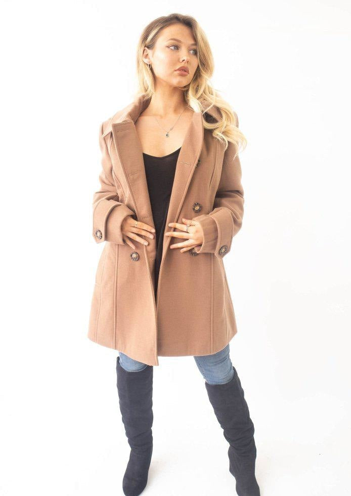 Woman wearing a beige coat and knee-high boots on a white background