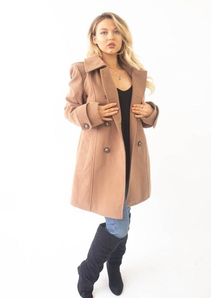 Woman wearing a tan coat on a white background