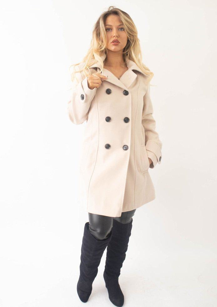 Woman wearing a beige trench coat and black knee-high boots on a white background
