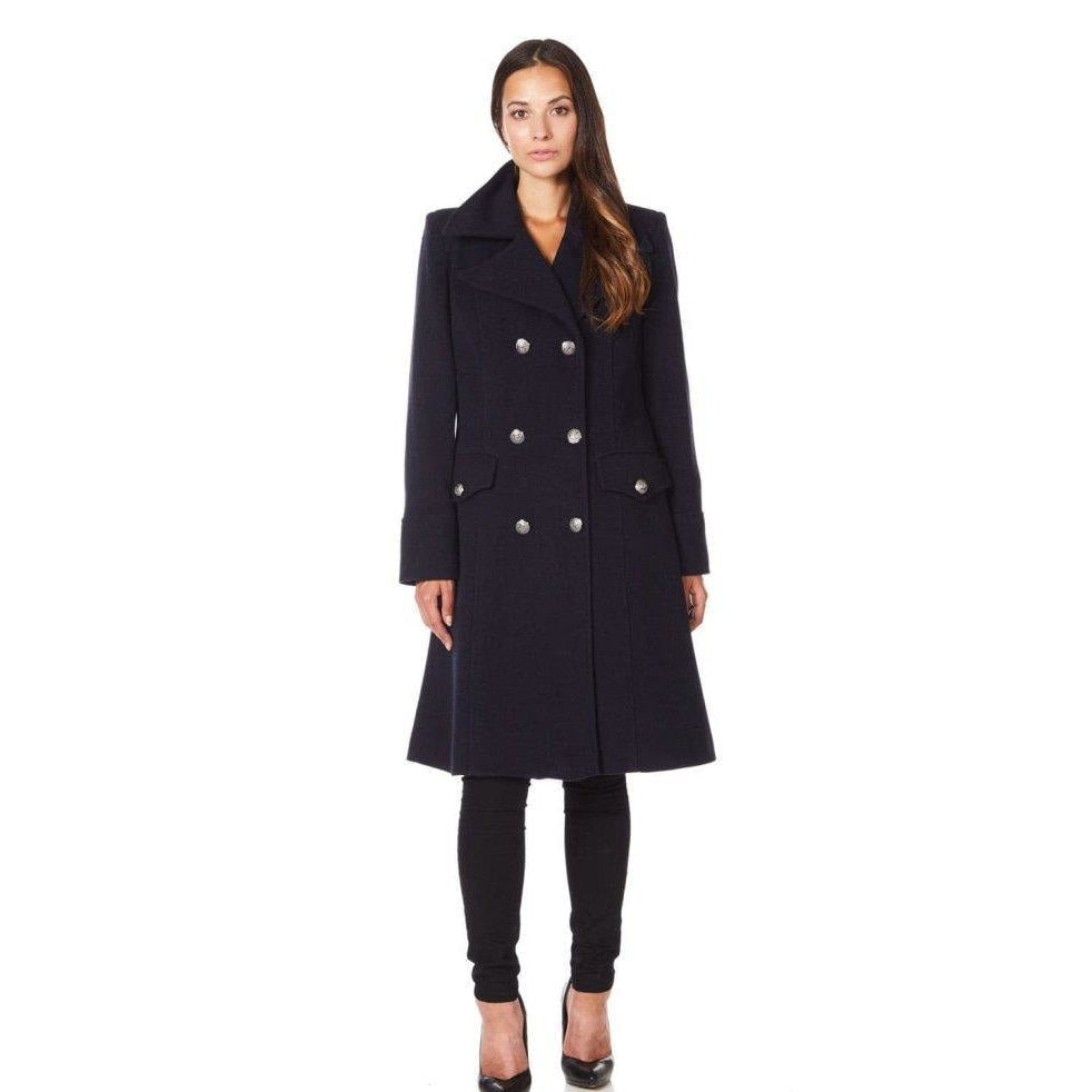Woman wearing a navy blue coat with silver buttons on a white background