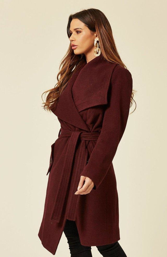 Woman wearing a burgundy coat on a beige background