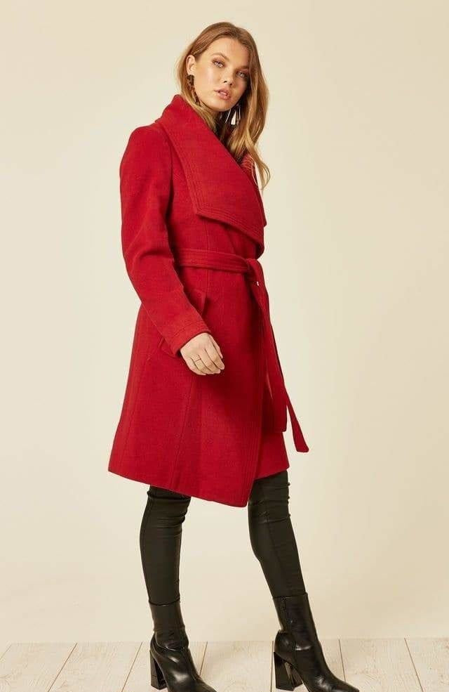 Woman wearing a red coat on a beige background