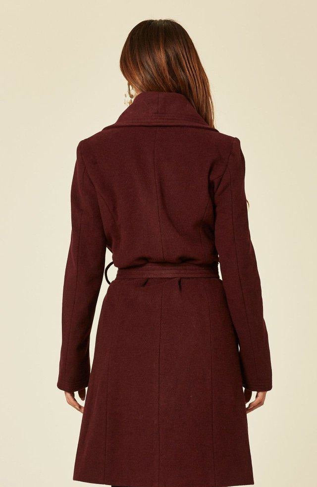 Woman wearing a burgundy coat on a beige background