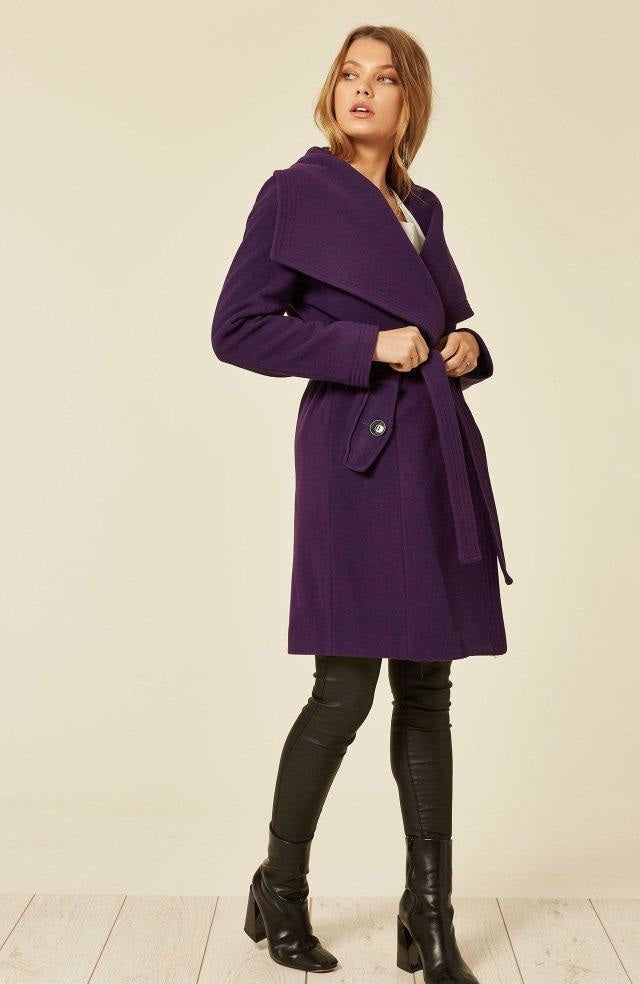 Woman wearing a purple coat with a plain background