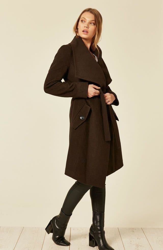 Woman wearing a brown coat on a plain background