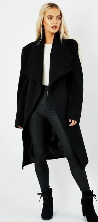 Woman wearing a black coat with a white background.