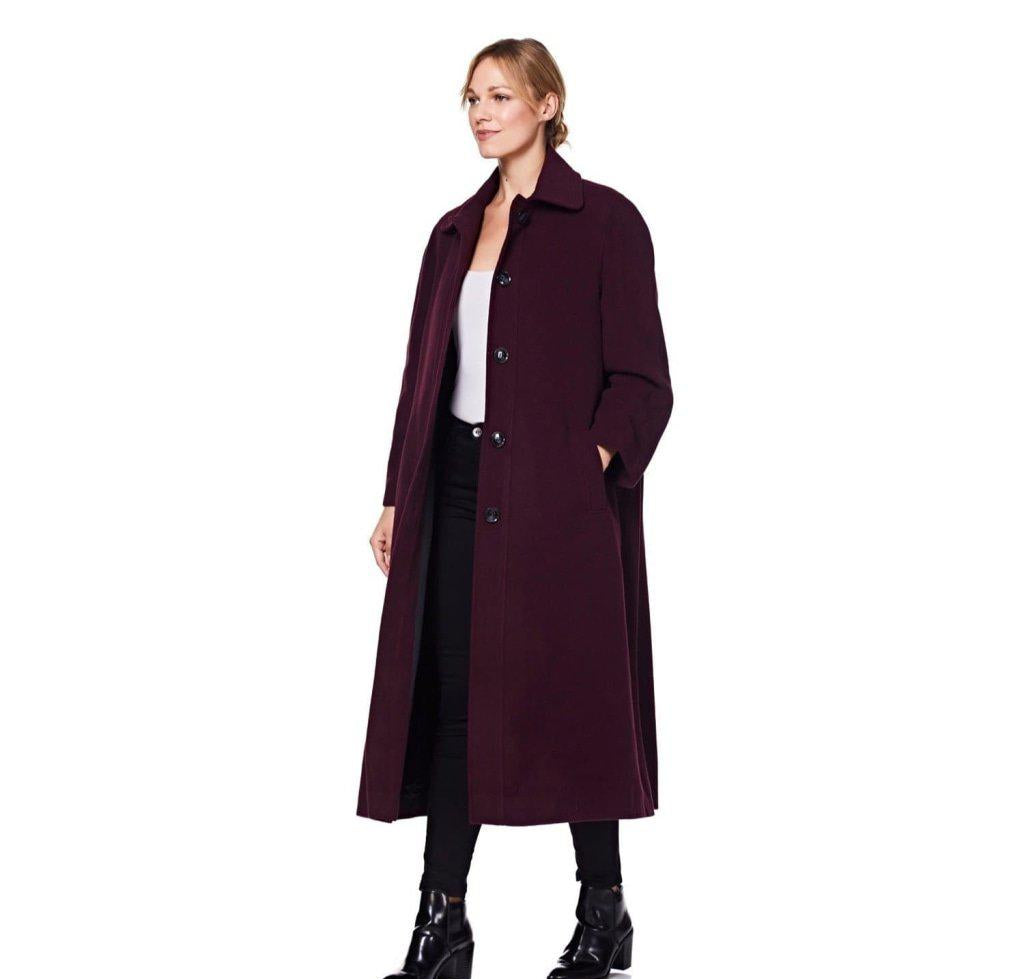 Woman wearing a long dark coat on a white background