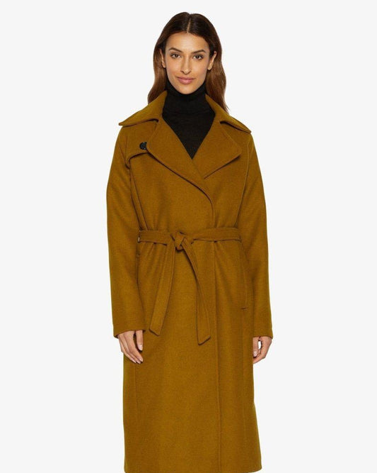 Woman wearing a long mustard yellow coat on a white background