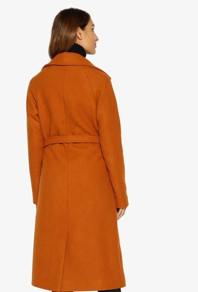 Woman wearing an orange coat on a white background
