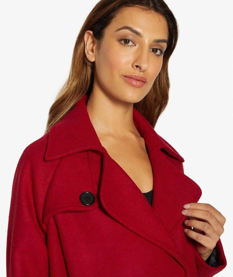 Woman wearing a red coat with a plain background