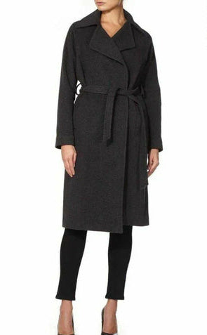 Woman wearing a dark gray coat with a belt, standing against a white background