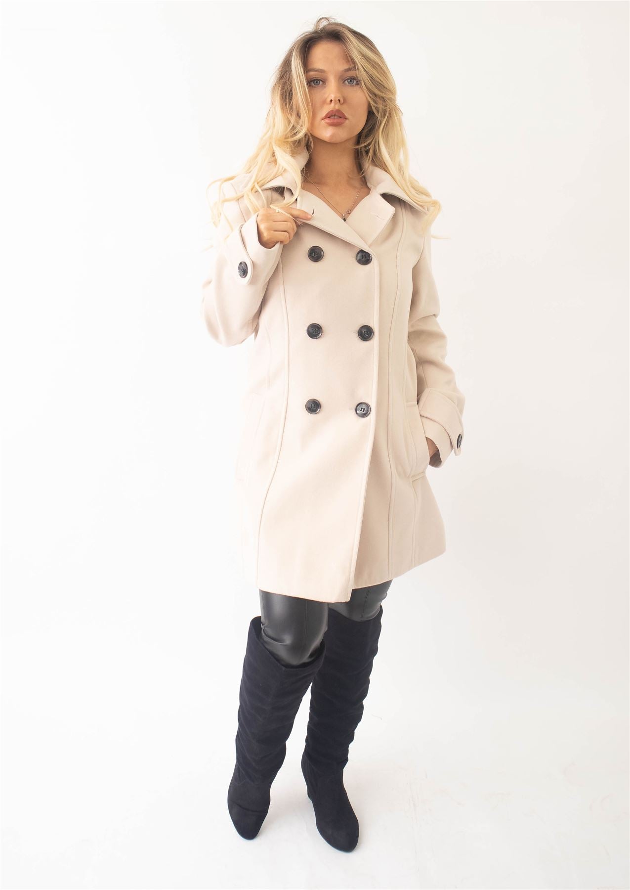 Woman wearing a beige coat with black buttons on a white background