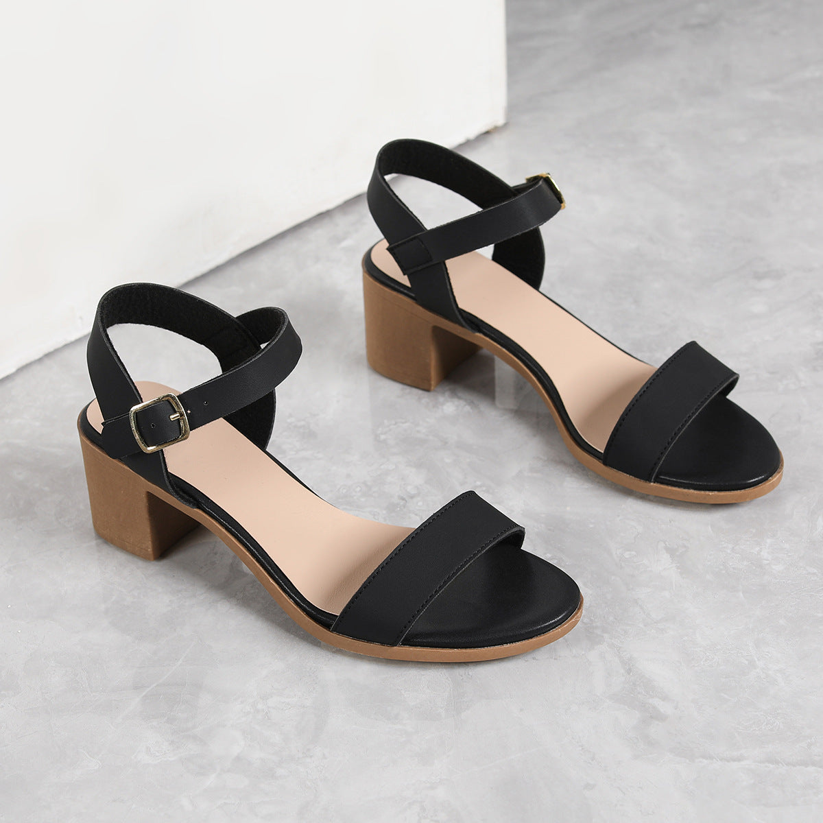 Black block-heel sandals on a light gray background