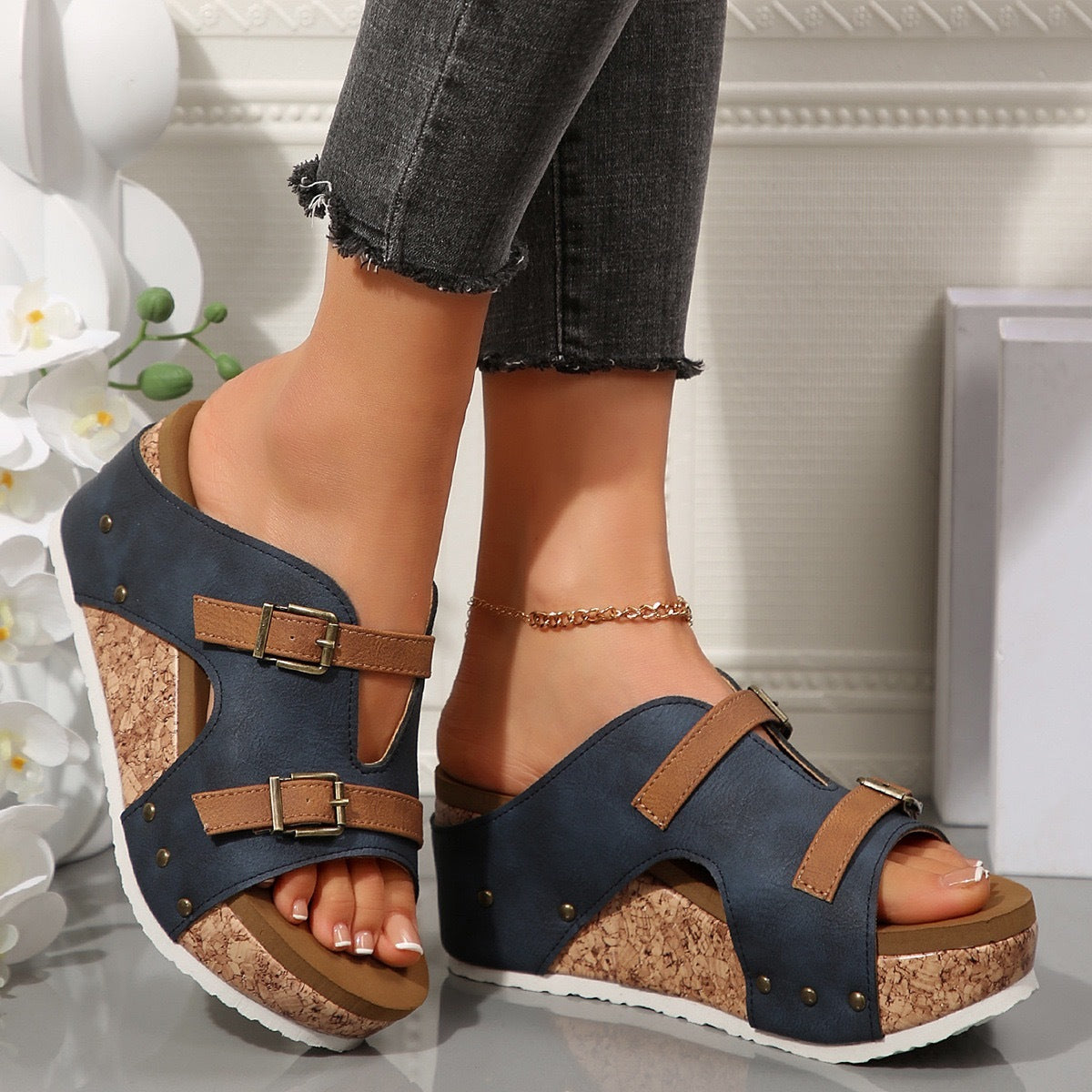 Navy sandals with brown accents worn by a person indoors.