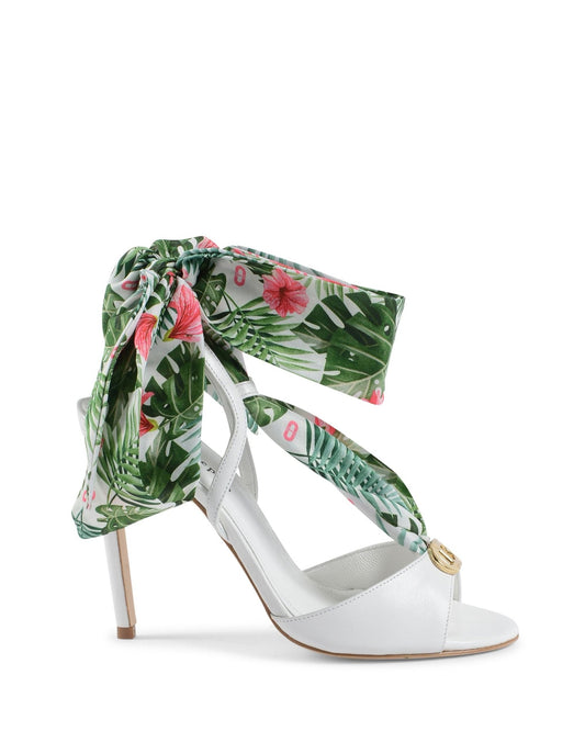 White high-heeled shoe with tropical leaf and flower patterned ribbon on a white background