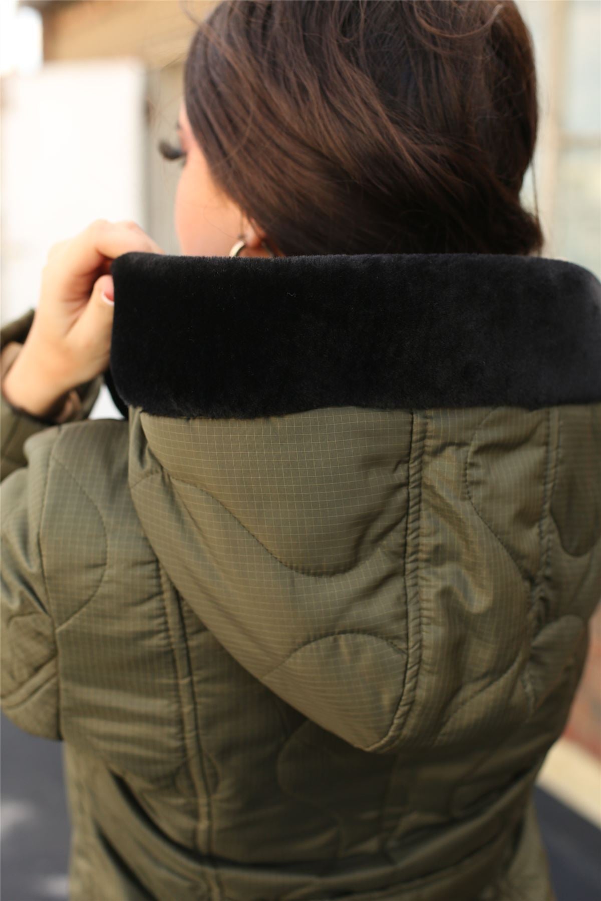 Person wearing a green jacket with a black fur-lined hood