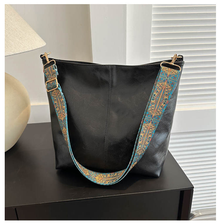 Black handbag with decorative strap on a table