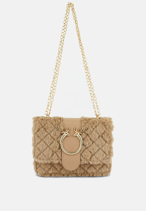 Beige quilted handbag with gold chain strap on a beige background