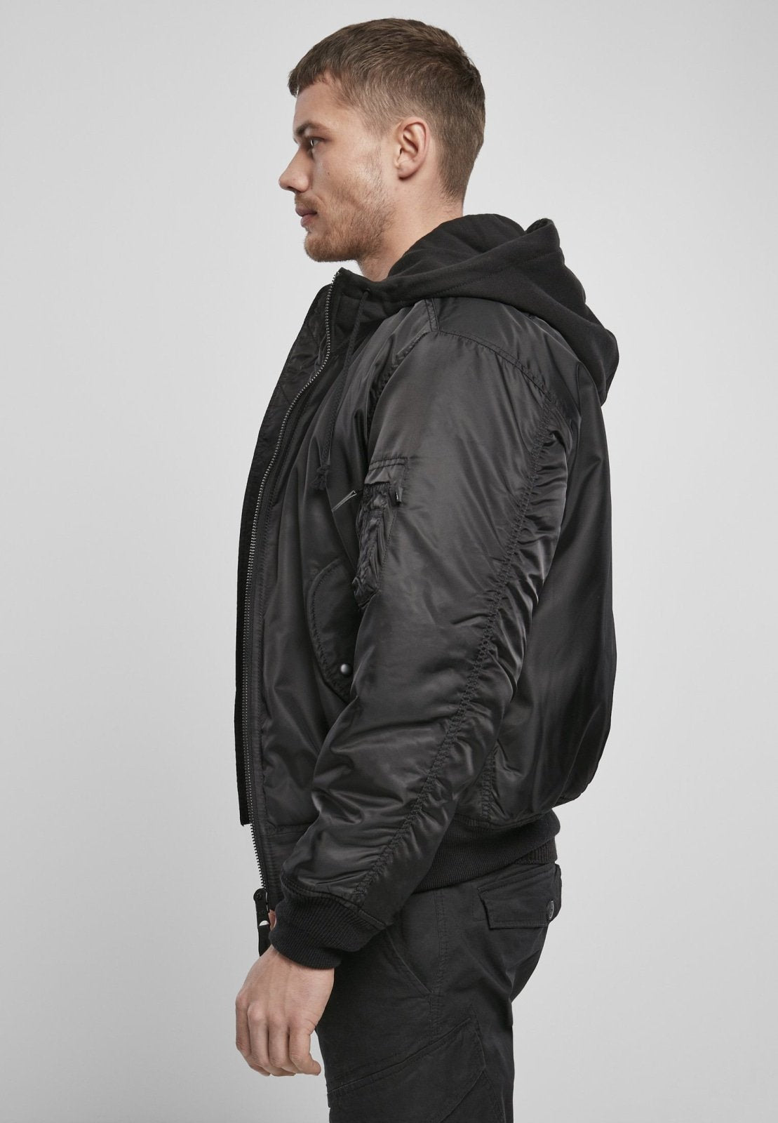 Man wearing a black bomber jacket on a light gray background