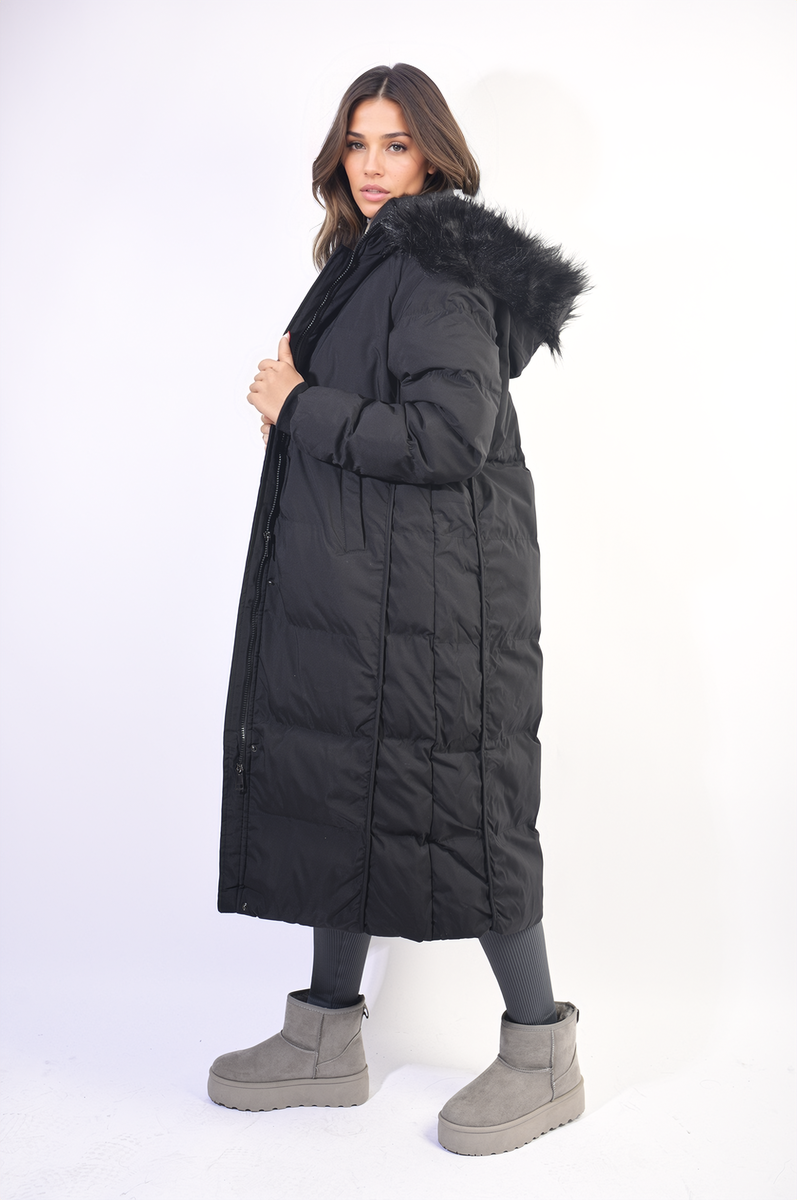 Woman wearing a long black puffer coat with fur hood on a white background