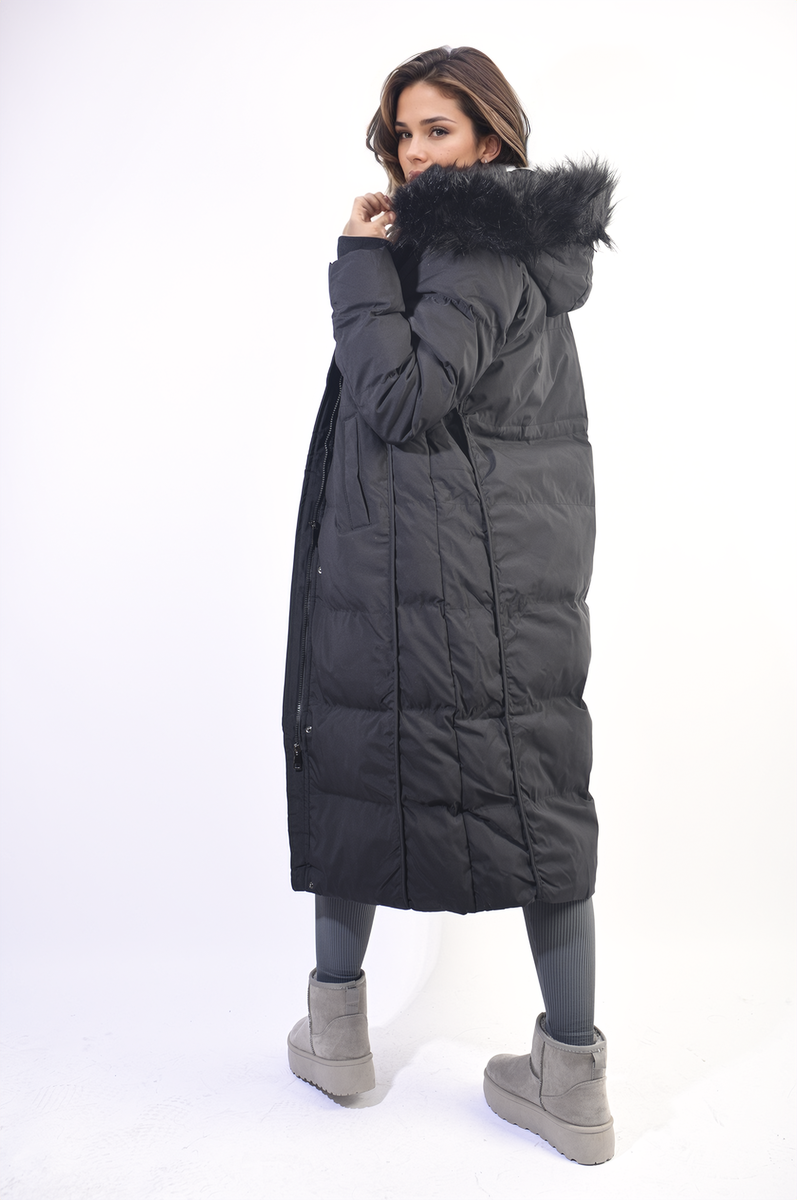 Woman wearing a long black puffer coat with fur hood on a white background