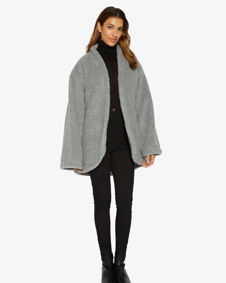 Woman wearing a gray coat over a black outfit on a white background