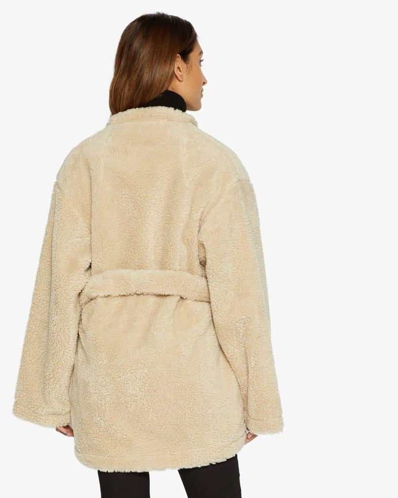 Woman wearing a beige sherpa coat on a white background