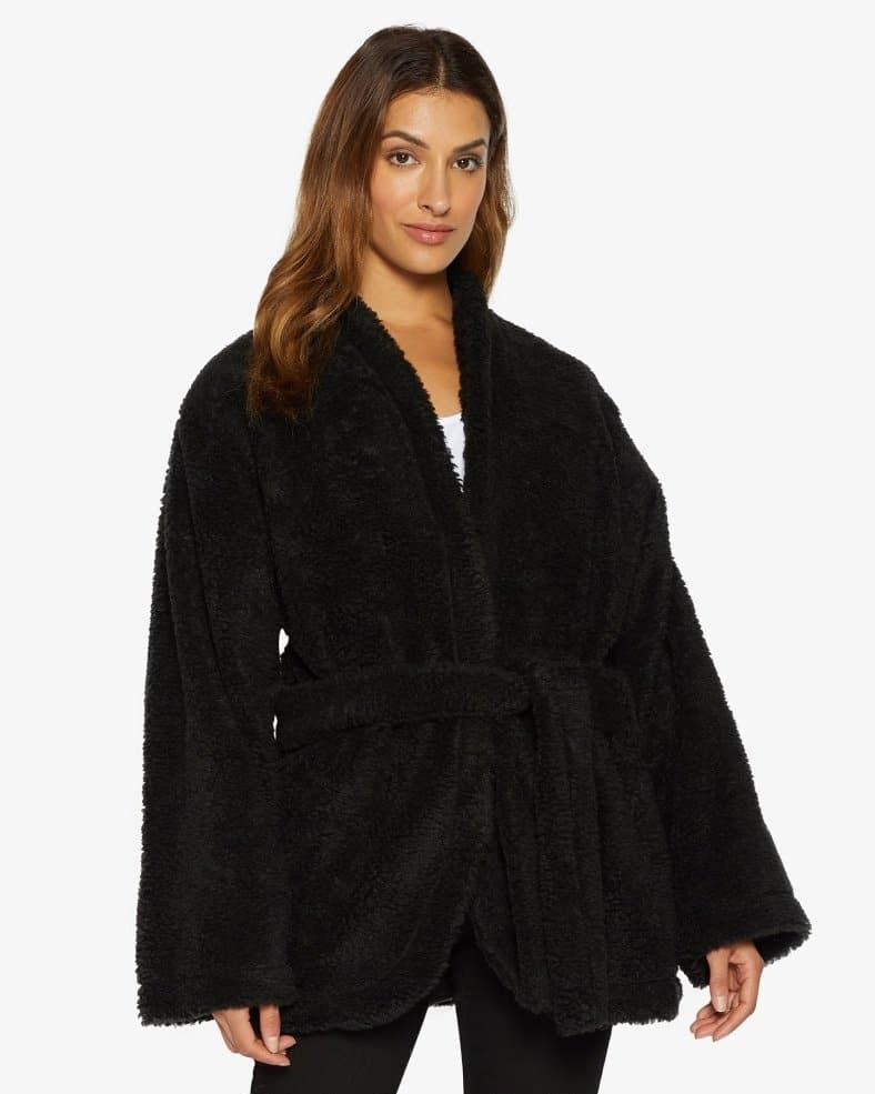 Woman wearing a black plush robe on a white background