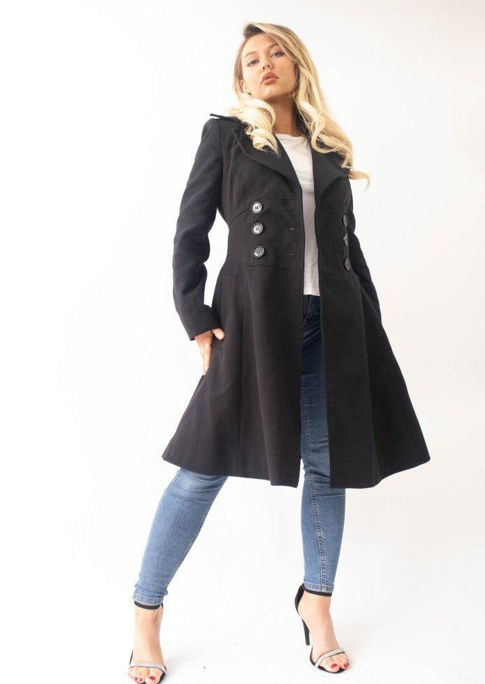 Woman wearing a black coat and blue jeans on a white background