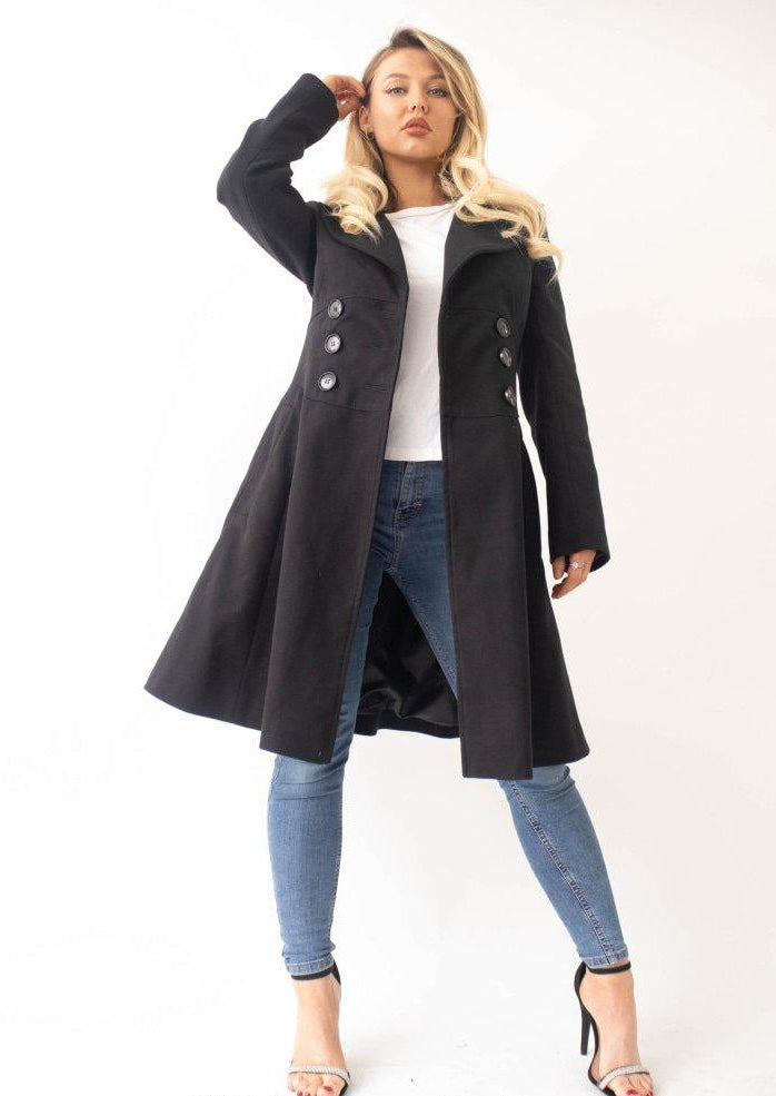 Woman wearing a black coat over a white top and blue jeans on a white background