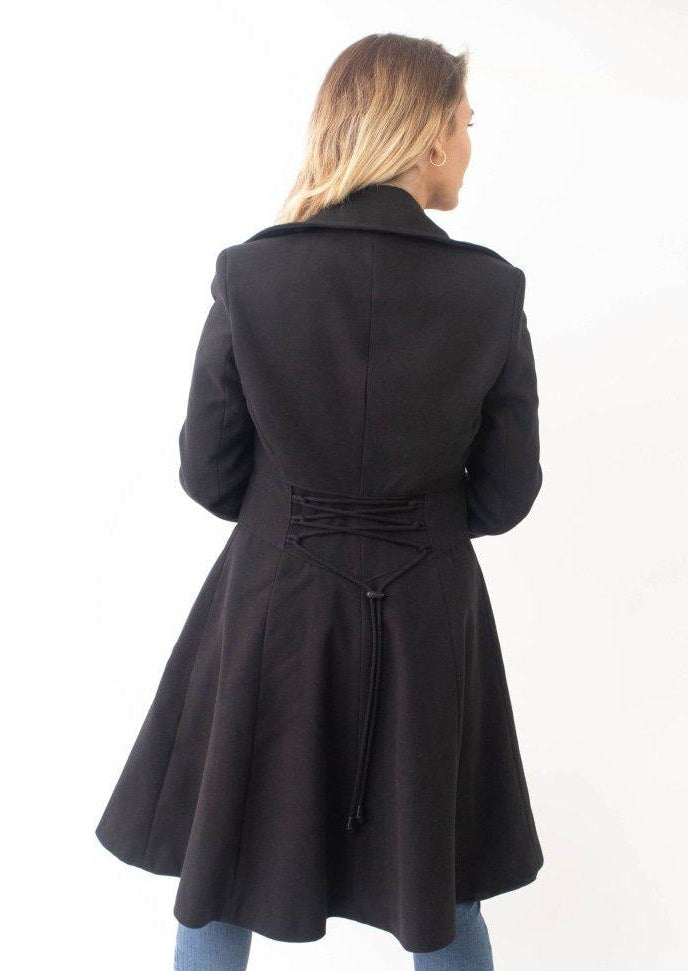 Woman wearing a black coat with a tie waist on a white background