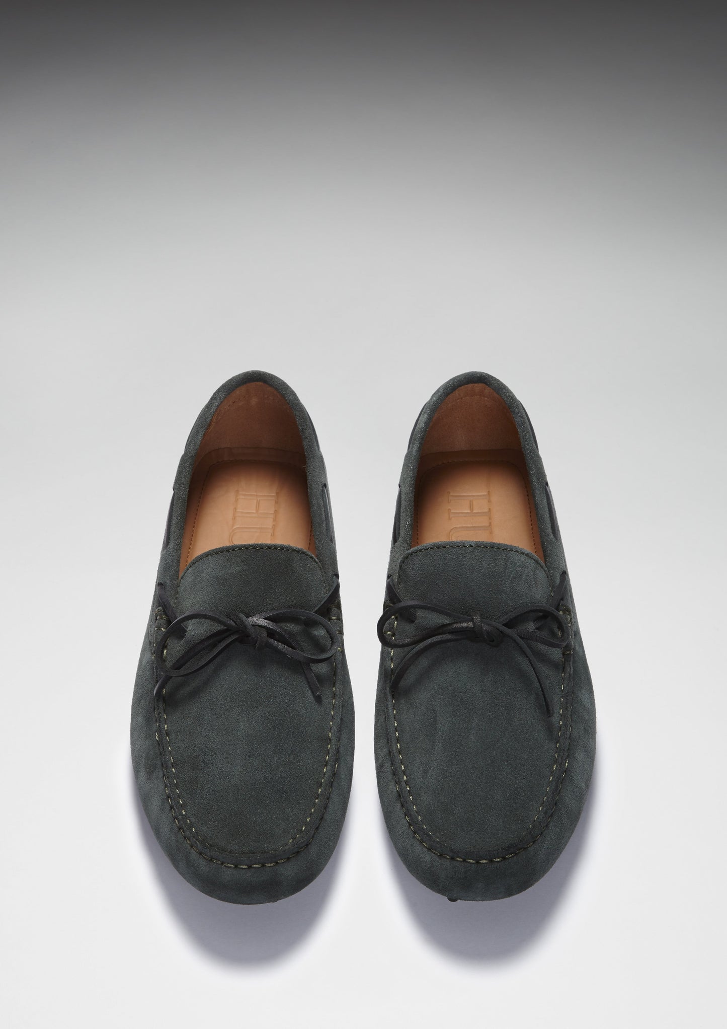 Pair of dark gray suede loafers on a light gray background