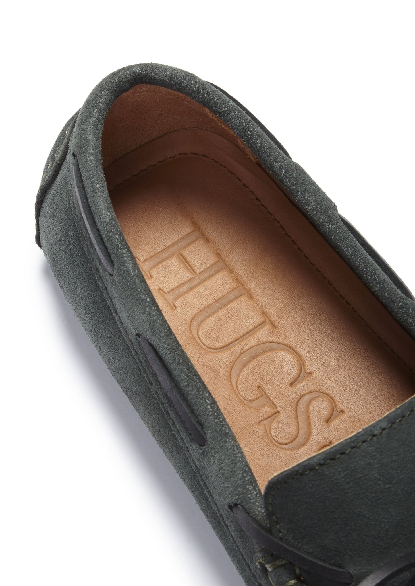 Close-up of a shoe with 'HUGS' embossed on the insole against a white background