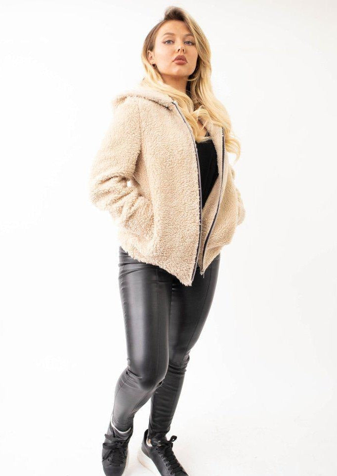 Woman wearing a beige sherpa jacket with a white background