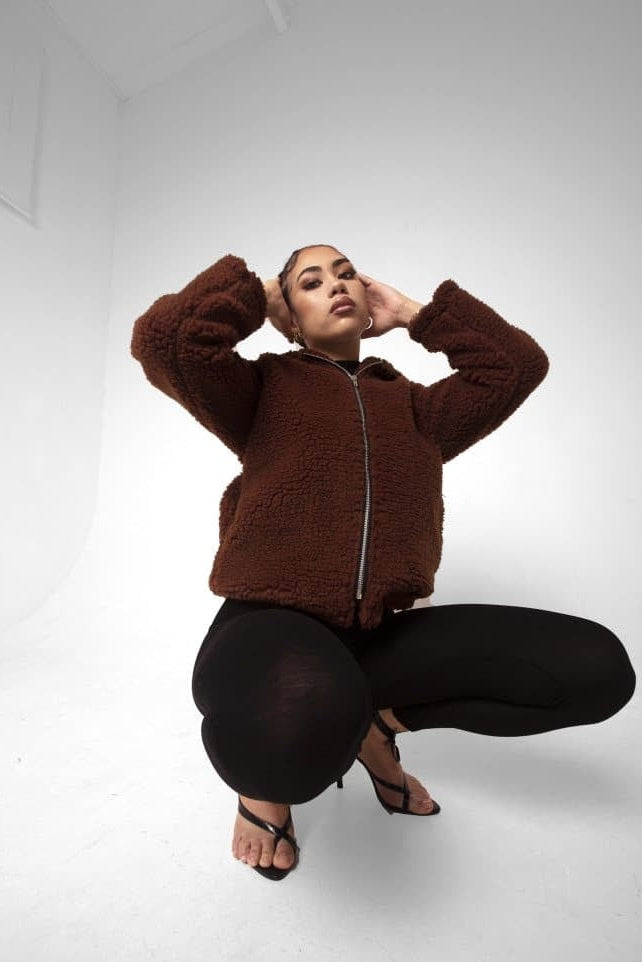 Person wearing a brown fleece jacket on a white background