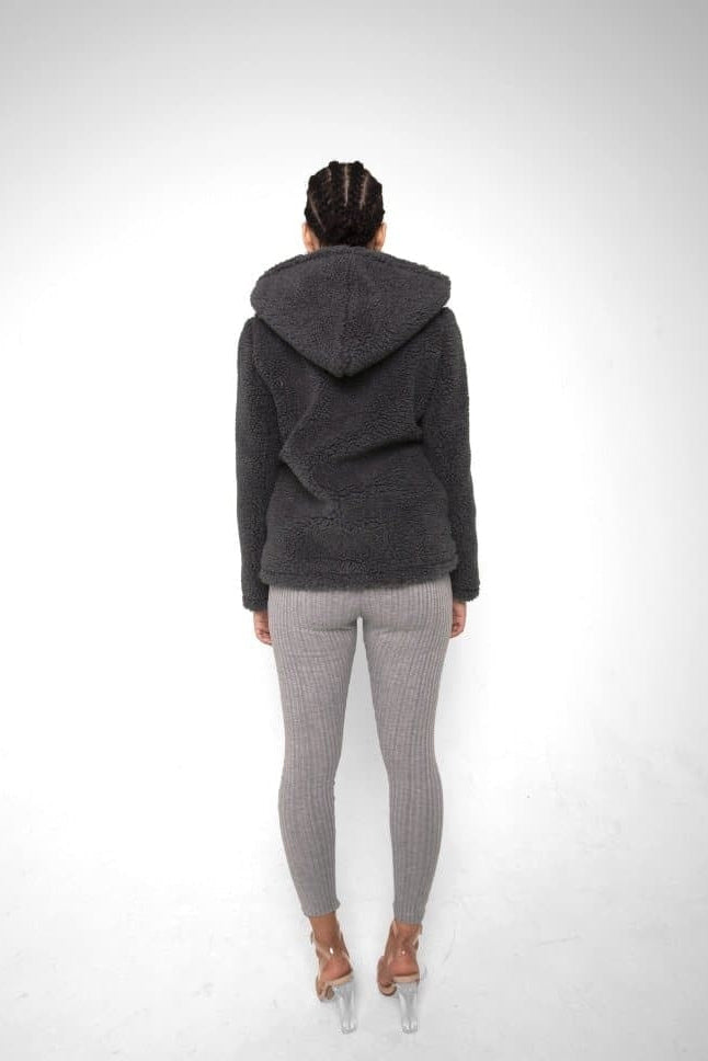 Person wearing a dark gray hoodie and patterned leggings on a white background