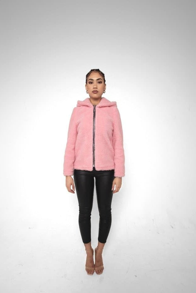 Person wearing a pink jacket and black pants on a white background