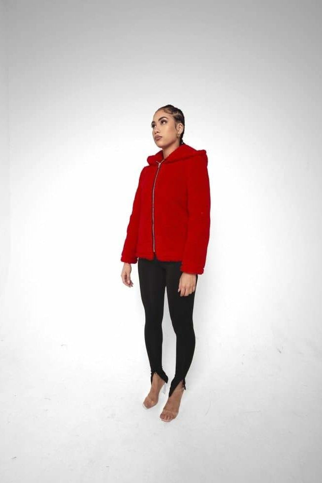 Person wearing a red jacket and black pants on a white background