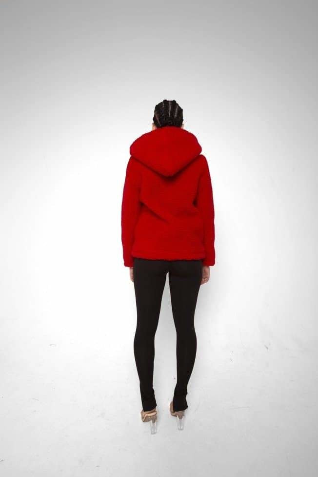Person wearing a red hoodie and black pants on a white background