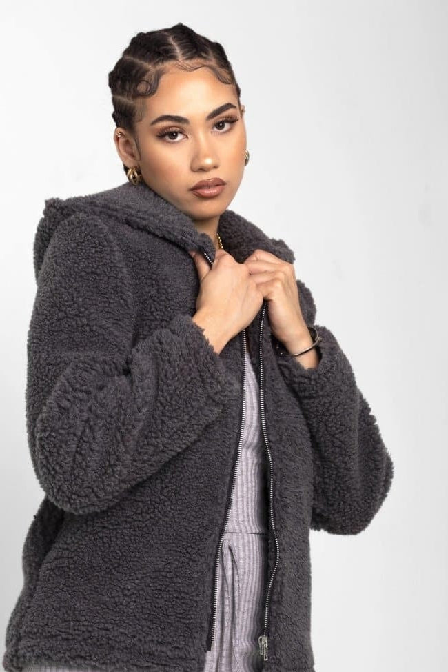 Woman wearing a dark gray fleece jacket on a white background