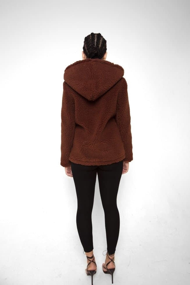 Person wearing a brown hooded jacket on a white background