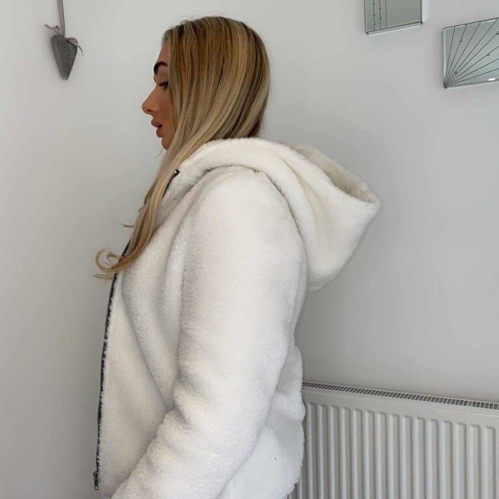 Person wearing a white fleece hoodie in a room with a radiator.