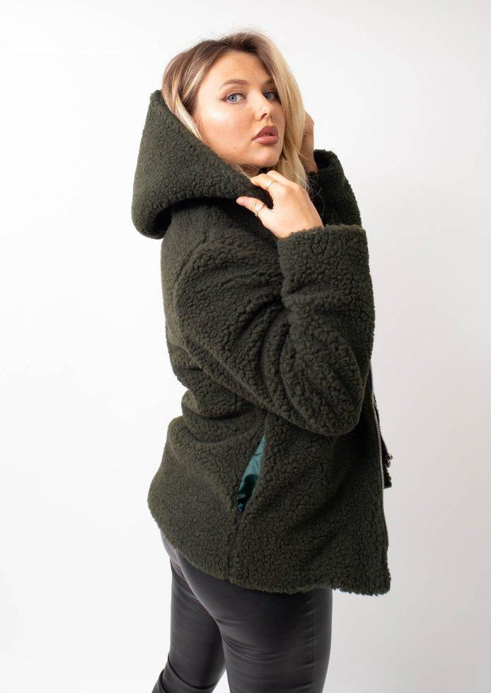 Woman wearing a green coat against a white background