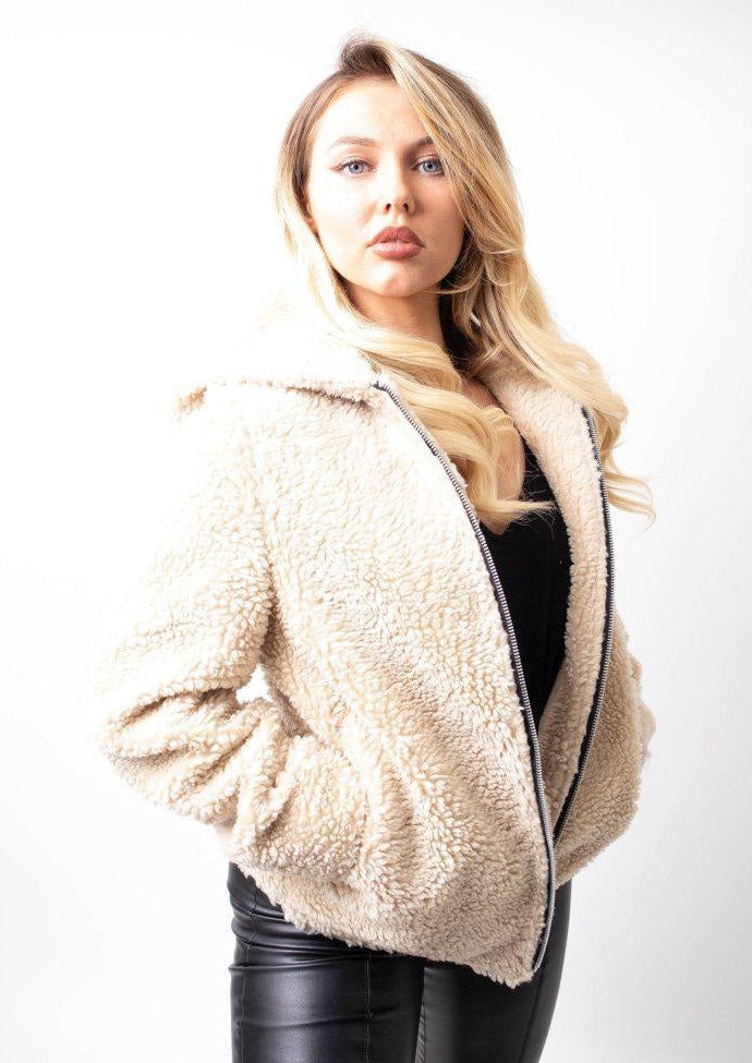 Woman wearing a beige sherpa jacket on a white background
